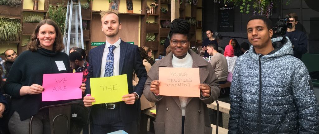 Group of four young people holding a sign that says 'We are the Young Trustees Movement'.